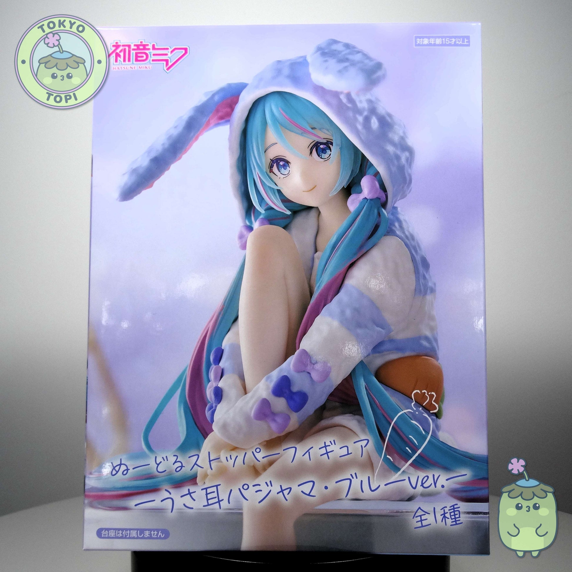 This officially licensed FuRyu figure captures Miku in charming bunny-eared pajamas, complete with a plush hooded design. Standing approximately 14 cm tall, the Noodle Stopper is engineered to perch securely on shelves, desks, or display edges, making it an ideal piece for expanding your Vocaloid collection vertically. The blue colourway and meticulous detailing showcase the character's signature aesthetic while maintaining the functional appeal collectors value in this figure format.
