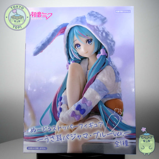 This officially licensed FuRyu figure captures Miku in charming bunny-eared pajamas, complete with a plush hooded design. Standing approximately 14 cm tall, the Noodle Stopper is engineered to perch securely on shelves, desks, or display edges, making it an ideal piece for expanding your Vocaloid collection vertically. The blue colourway and meticulous detailing showcase the character's signature aesthetic while maintaining the functional appeal collectors value in this figure format.