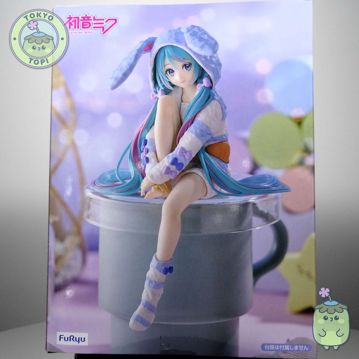 This officially licensed FuRyu figure captures Miku in charming bunny-eared pajamas, complete with a plush hooded design. Standing approximately 14 cm tall, the Noodle Stopper is engineered to perch securely on shelves, desks, or display edges, making it an ideal piece for expanding your Vocaloid collection vertically. The blue colourway and meticulous detailing showcase the character's signature aesthetic while maintaining the functional appeal collectors value in this figure format.