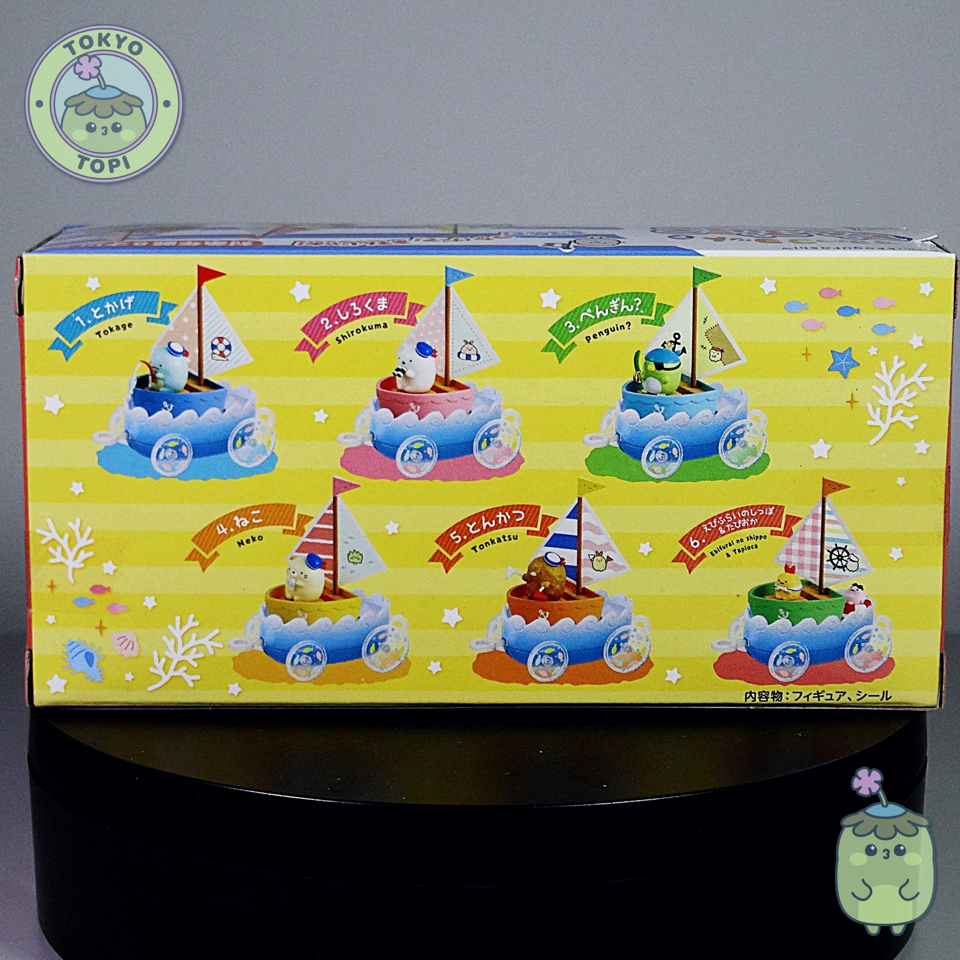 Box of toy boats with colorful designs on a gray background