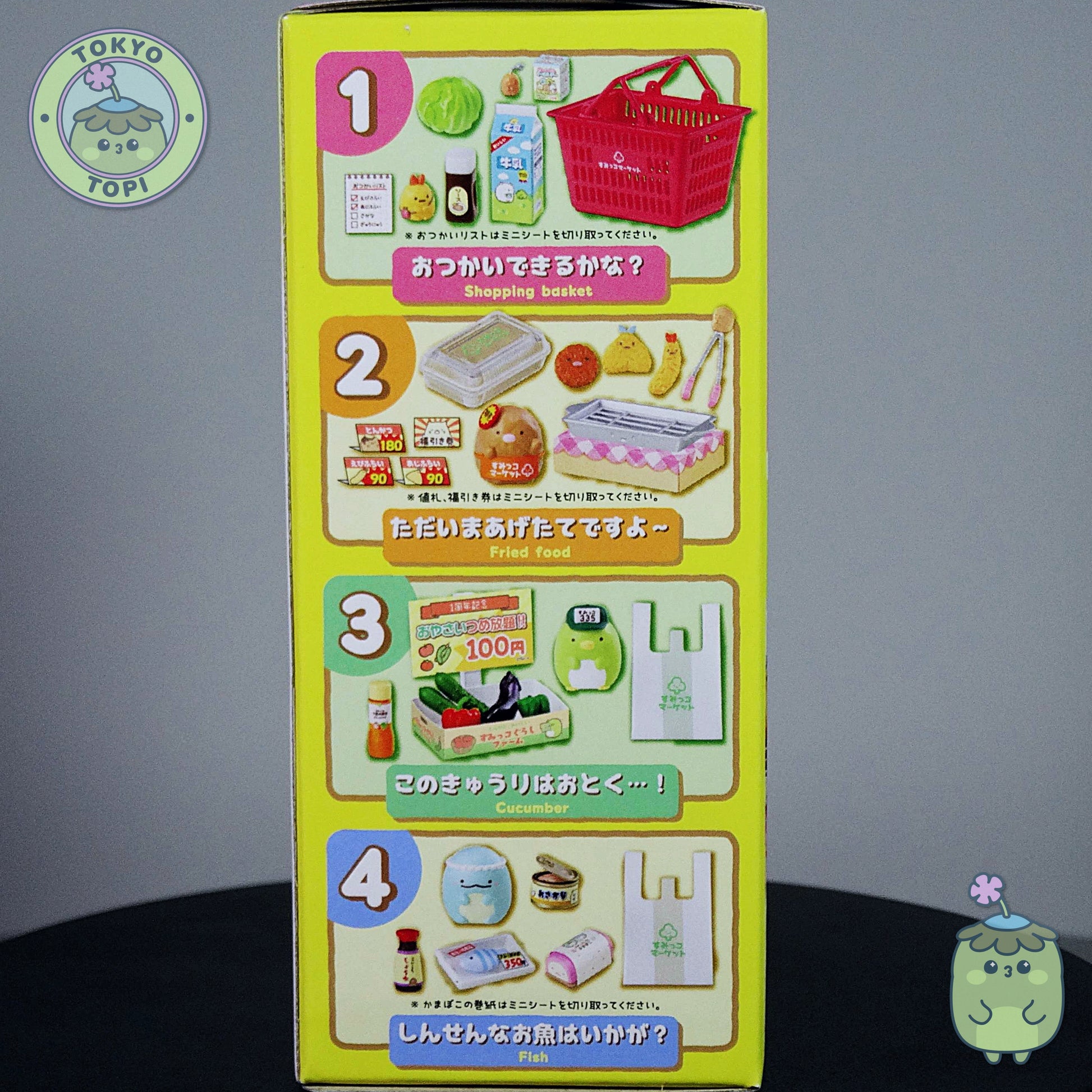 Toy packaging with illustrations of a shopping basket, food items, and other toys on a gray background.